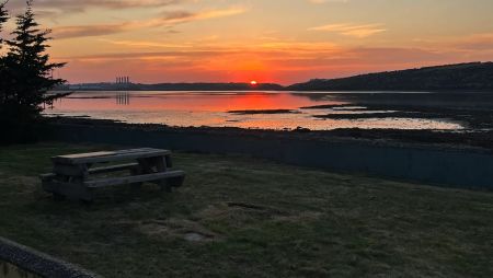 The garden showing the picnic bench looking over the river while the sun sets in the distance.